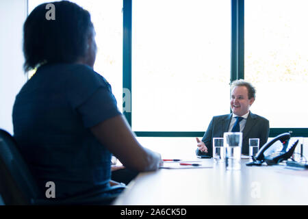 Eine schwarze Frau sitzt an einem Tisch in einer Chancengleichheit Business Stockfoto