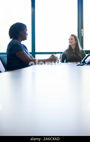 Eine schwarze Frau sitzt an einem Tisch in einer Chancengleichheit Business Stockfoto