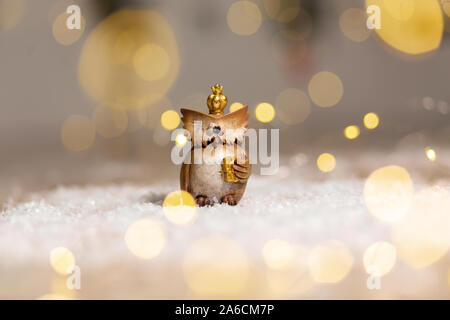 Dekorative figurine toy Eule mit einer goldenen Krone auf dem Kopf. Festliches Dekor, warme Bokeh leuchtet. Stockfoto