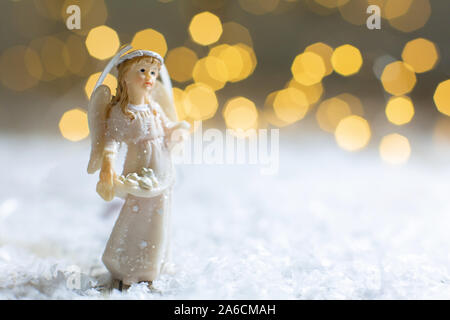 Die dekorativen Weihnachts-themed Figuren. Statuette eines Weihnachten Engel. Weihnachtsdekoration. Festliches Dekor, warme Bokeh leuchtet Stockfoto