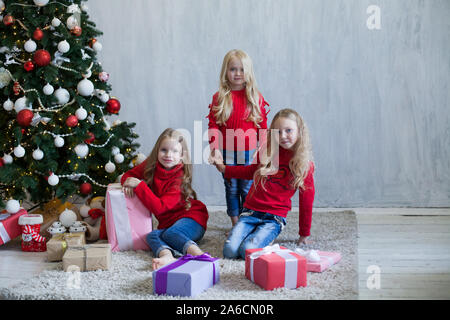 Drei Mädchen Schwestern öffnen Weihnachtsgeschenke am Weihnachtsbaum neues Jahr Stockfoto