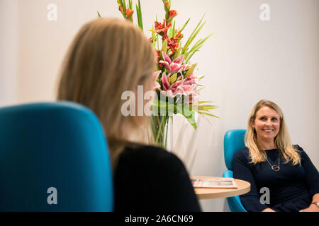 Zwei intelligente Frauen sitzen in großen Stühlen in einer modernen Büroumgebung Stockfoto