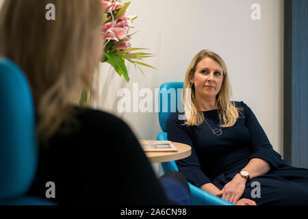 Zwei intelligente Frauen sitzen in großen Stühlen in einer modernen Büroumgebung Stockfoto