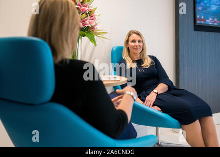 Zwei intelligente Frauen sitzen in großen Stühlen in einer modernen Büroumgebung Stockfoto