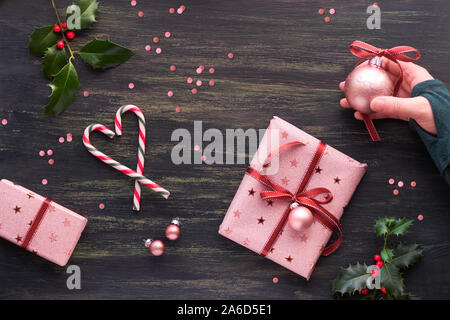 Festliche dunkle Weihnachten Hintergrund mit rosa Geschenkboxen, gestreifte Zuckerstangen in Form der Herzen, Schmuckstücke und dekorative Sterne, kreative Flach mit X Stockfoto