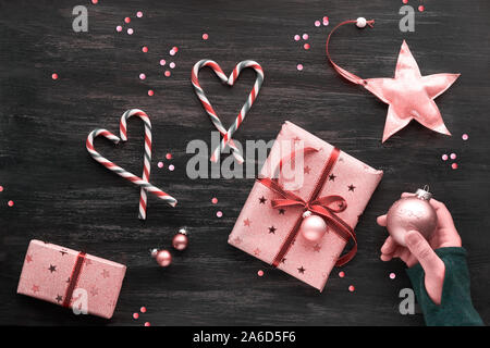 Festliche dunkle Weihnachten Hintergrund mit rosa Geschenkboxen, gestreifte Zuckerstangen in Form der Herzen, Schmuckstücke und dekorative Sterne, geometrische Creative flach Stockfoto