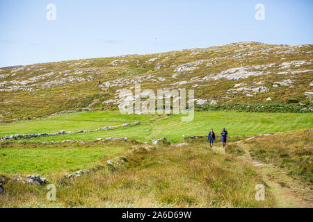 Zwei Männer, die auf dem Wanderweg zum Three Castle Head in Dunlough, Westirland, wandern. Klarer blauer Himmel. Stockfoto