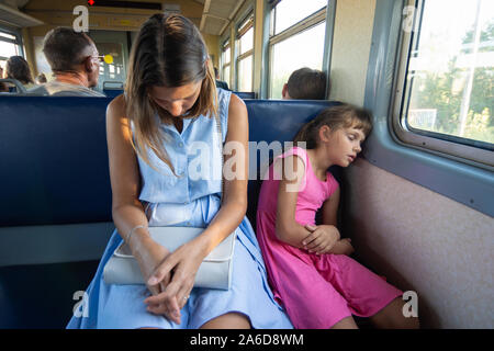 Müde Mutter und Tochter schlafen Sie tief in eine elektrische Eisenbahn Stockfoto