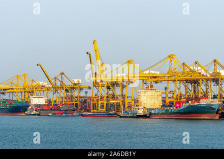 Laem Chabang Seehafen, Thailand - 17. März 2019: Mehrere angedockt Containerschiffe in verschiedenen Größen von der gelben Krane unter Sonnenuntergang Himmel gearbeitet wird. Stockfoto