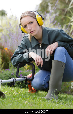 Junge Frau das Tragen von Gehörschutz in einem Garten Stockfoto