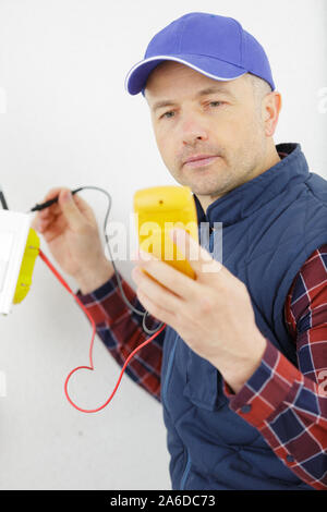 Elektriker die Messung der Spannung der Kabel an der Decke im Innenbereich Stockfoto