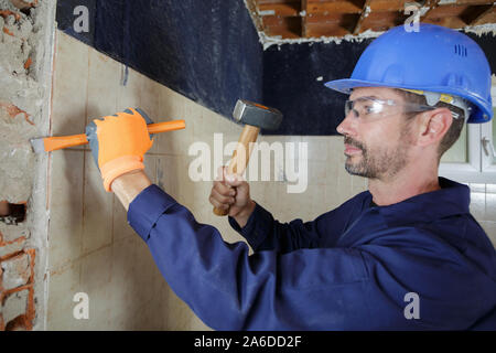 Männliche Builder mit dem Hammer auf die innere Wand Meißel Stockfoto