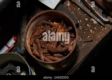 Rostige Schrauben und Schrauben in Metall Box auf der Werkbank. Stockfoto