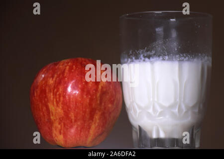 Glas Milch und roter Apfel auf dunklen und Unschärfe Hintergrund Stockfoto