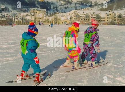 Drei junge zum ersten Mal Skifahrer auf einem schneebedeckten Hang während einer Lektion an der Beaver Creek Ski Schule in den Bergen von Colorado, USA. Die Skikurse in Beaver Creek Resort sind für unterschiedliche Altersgruppen konzipiert, beginnend mit diesen drei- bis vierjährige Kinder in ihren bunten Snowsuits. Stockfoto