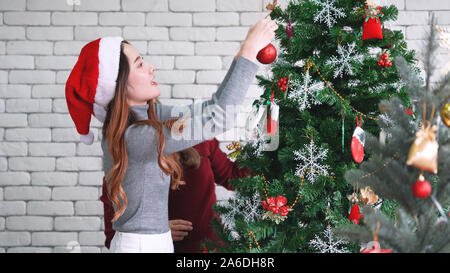 Asiatische Frau schmücken Weihnachtsbaum, die Vorbereitung auf Weihnachten im Dezember Stockfoto