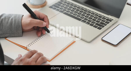 7/8 shot professioneller Geschäftsmann sein Projekt arbeiten beim Schreiben Ideen auf Notebook Stockfoto