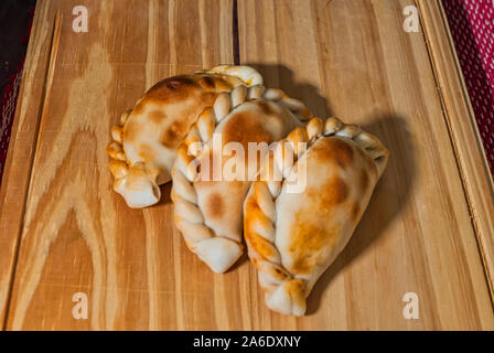 Holztisch mit frischen, hausgemachten Empanadas (detaillierte Nahaufnahme; selektive Fokus) Stockfoto