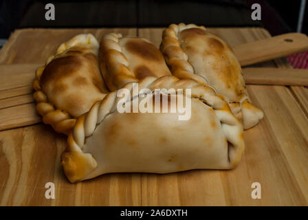 Holztisch mit frischen, hausgemachten Empanadas (detaillierte Nahaufnahme; selektive Fokus) Stockfoto