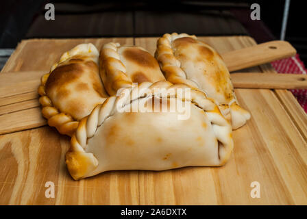 Holztisch mit frischen, hausgemachten Empanadas (detaillierte Nahaufnahme; selektive Fokus) Stockfoto