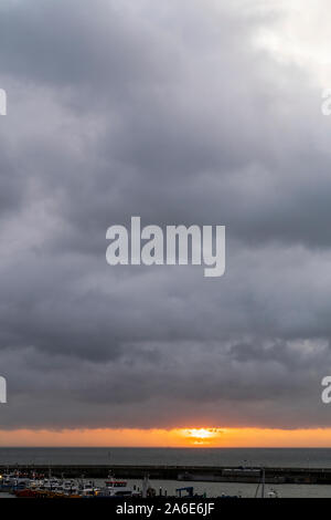 Sonnenaufgang über dem Ärmelkanal, Meer, von Sarre in Kent, England. Graue Gewitterwolken Overhead mit einem dünnen Band von Orange Sky am Horizont als die Sonne hinter Wolken. Stockfoto