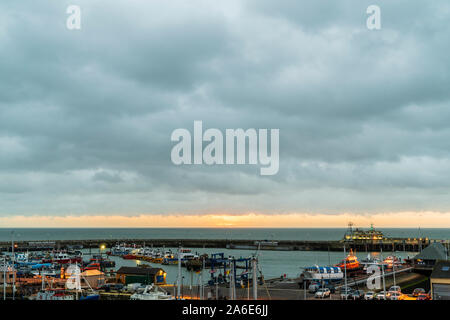 Dawn und der tagesanbruch über den Ärmelkanal, Meer und Hafen von Ramsgate, Kent, England. Graue Gewitterwolken Overhead mit einem dünnen Band von Orange Sky am Horizont, bevor die Sonne aufgeht. Stockfoto