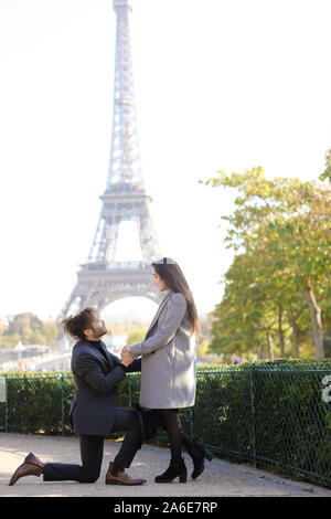 Afro-amerikanische glücklich Mann, der Vorschlag mit kaukasischen Freundin in Paris, Eiffel Turm im Hintergrund. Stockfoto