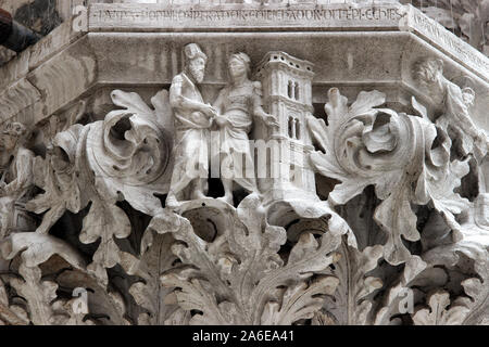 Detailansicht eines geschnitzten gotischen Steinkapitells mit Relieffiguren und Akanthusblättern an der Fassade des Dogenpalasts in Venedig, Italien Stockfoto