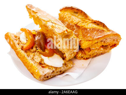 Traditionelle französische Pan bagnat - lecker Sandwich mit Thunfisch, hart gekochte Eier, Sardellen und geschmorte Paprika. Auf weissem Hintergrund Stockfoto