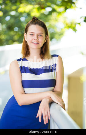 Junge Mädchen in blauem Kleid stehen auf Stadt Brücke umgeben von Bäumen Stockfoto