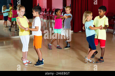 Gruppe von fröhlichen positive lächelnde Kinder versucht, Tanzen mit Partner im Klassenzimmer Stockfoto