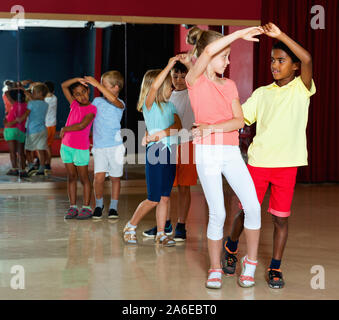 Lächelnd glückliche Kinder der Grundschule versucht, tanzen Salsa tanzen im modernen Studio Stockfoto