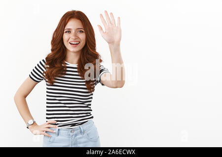 Hallo, wie sie tut. Gut gelaunt freundlich nett redhead Jugendmädchen in gestreiften T-Shirt heben die Hand und fröhlich winkend, lächelnd sagen Hallo, willkommen Gäste Stockfoto