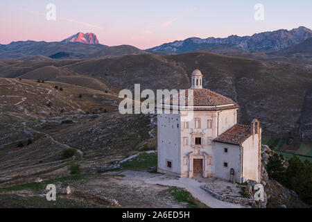 Schöne Kapelle Chiesa di Santa Maria della Pietà bei Sonnenaufgang mit kargen Landschaft und alpine leuchtende Berg des Corno Grande im Hintergrund, Rocca C Stockfoto