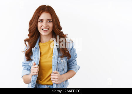 Stilvolle und durchsetzungsfähige zuversichtlich kaukasischen rothaarige Mädchen, die versuchen, auf Jeansjacke, lächelt selbstbewusst und zufrieden, Ziel, Erfolg, Gefühl gefördert und Stockfoto