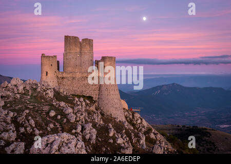 Die Ruinen der mittelalterlichen Burg Rocca Calascio nach dem Sonnenuntergang und Mond mit Berglandschaft und bunte Himmel im Hintergrund, Abruzzen, Italien Stockfoto