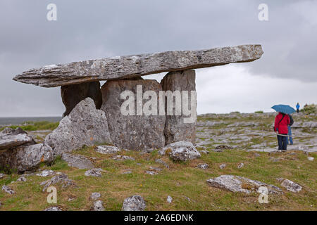 Touristen besuchen Poulnabrone Grab bei Regenwetter, Burren, Republik von Irland. Stockfoto