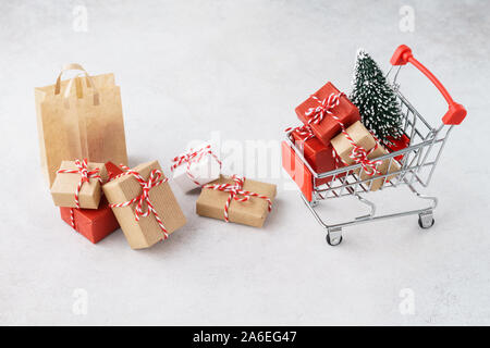 Warenkorb oder Trolley voller Geschenkboxen und einen Weihnachtsbaum. Weihnachten Verkauf Konzept. Stockfoto