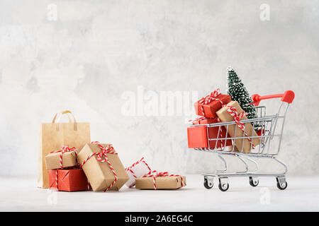 Warenkorb oder Trolley voller Geschenkboxen und einen Weihnachtsbaum. Weihnachten Verkauf Konzept. Kopieren Sie Platz. Stockfoto