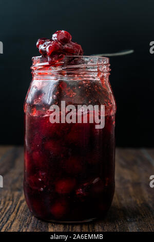 Cranberry Marmelade im Glas mit Löffel/Cranberries Marmelade serviert mit Scheiben Brot zum Frühstück. Stockfoto