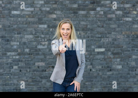 Enthusiastisch motivierten attraktive Frau mittleren Alters, die ein "Daumen hoch" Geste der Anerkennung und Erfolg mit einem strahlenden Lächeln Stockfoto