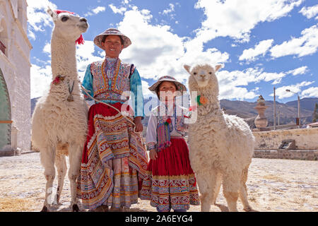 Das Porträt einer Mutter und ihrer Tochter mit einem Lama und Alpaka in Maca, Peru. Stockfoto