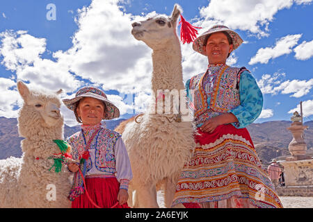 Das Porträt einer Mutter und ihrer Tochter mit einem Lama und Alpaka in Maca, Peru. Stockfoto