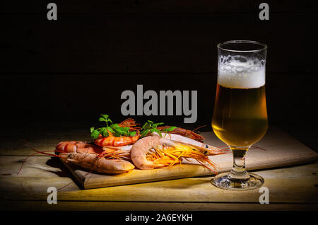 Glas kaltes Bier mit leckeren Shrimps, serviert auf einem hölzernen Bar oder pub Zähler für leckere Snacks. Stockfoto