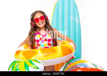 Coole Mädchen mit langen gekreuzigt Haar in Sonnenbrille und Sonnencreme, steht in der Nähe von aufblasbaren Matratzen in einem Ring aus Gummi lächeln Stockfoto