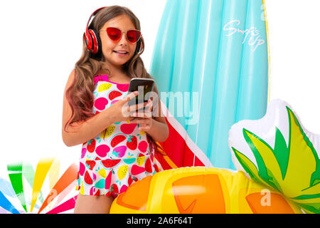 Coole Mädchen mit langen gekreuzigt Haar in Sonnenbrille und Sonnencreme, steht in der Nähe von aufblasbaren Matratzen und mit Freunden chatten und Lächeln Stockfoto