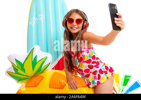 Coole Mädchen mit langen gekreuzigt Haar in Sonnenbrille und Sonnencreme, steht in der Nähe von aufblasbaren Matratzen und selfie mit einem Gummiring tun Stockfoto