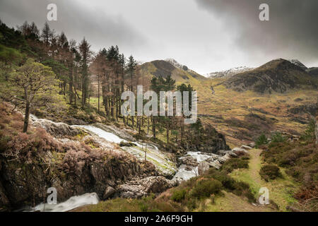 Wunderschöne Landschaft Bild der Ogwen Valley River und Wasserfälle im Winter mit schneebedeckten Bergen im Hintergrund Stockfoto