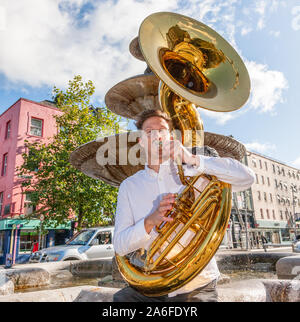 Die Stadt Cork, Cork, Irland. 26. Oktober, 2019. Sousaphon Spieler James Hobbis von Hyde Park Messing wird fertig für eine improvisierte Performance für die Öffentlichkeit über die Grand Parade während der Jazz Festival in Cork, Irland. - Gutschrift; David Creedon/Alamy leben Nachrichten Stockfoto