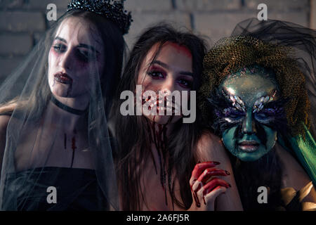 Drei Frauen in einem Karneval Kostüme von einem Vampir Braut in schwarz Hochzeit Kleid, schwarz Schleier und Diadem. Halloween Konzept. Stockfoto